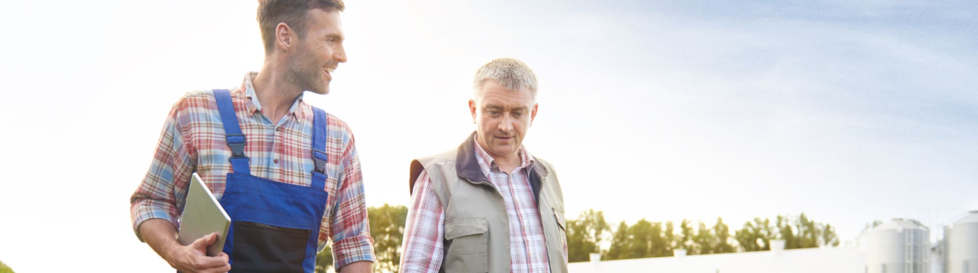 Deux agriculteurs en train de parcourir une exploitation de grandes cultures qui échangent leurs retours d’expérience.