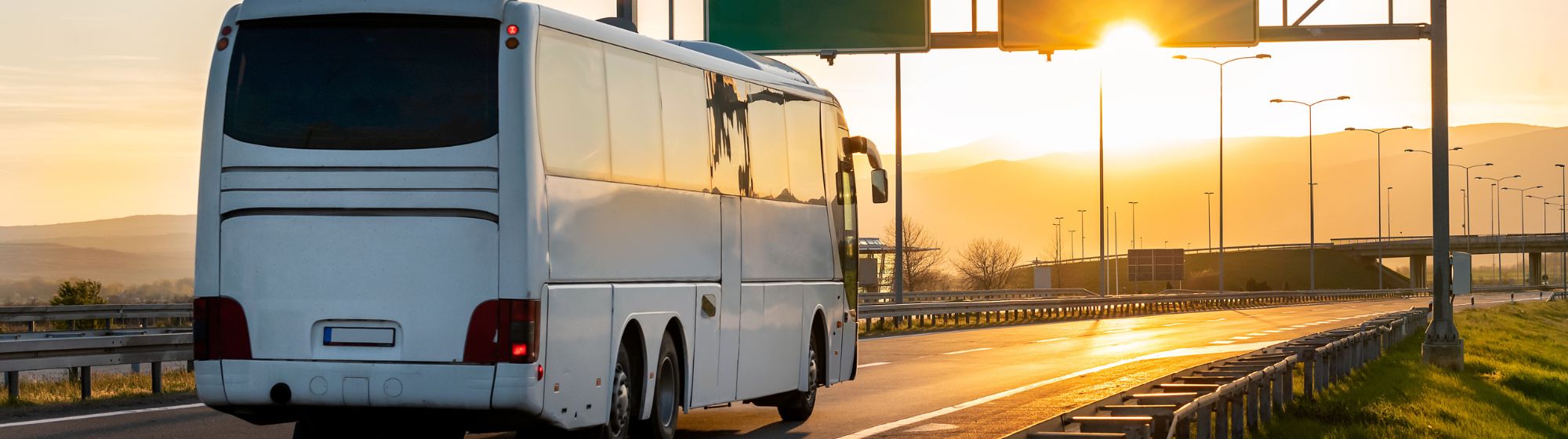 A bus on a motorway at sunset.
