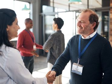 Un exposant joyeux qui sert à la main à une personne dans un contexte conviviale.